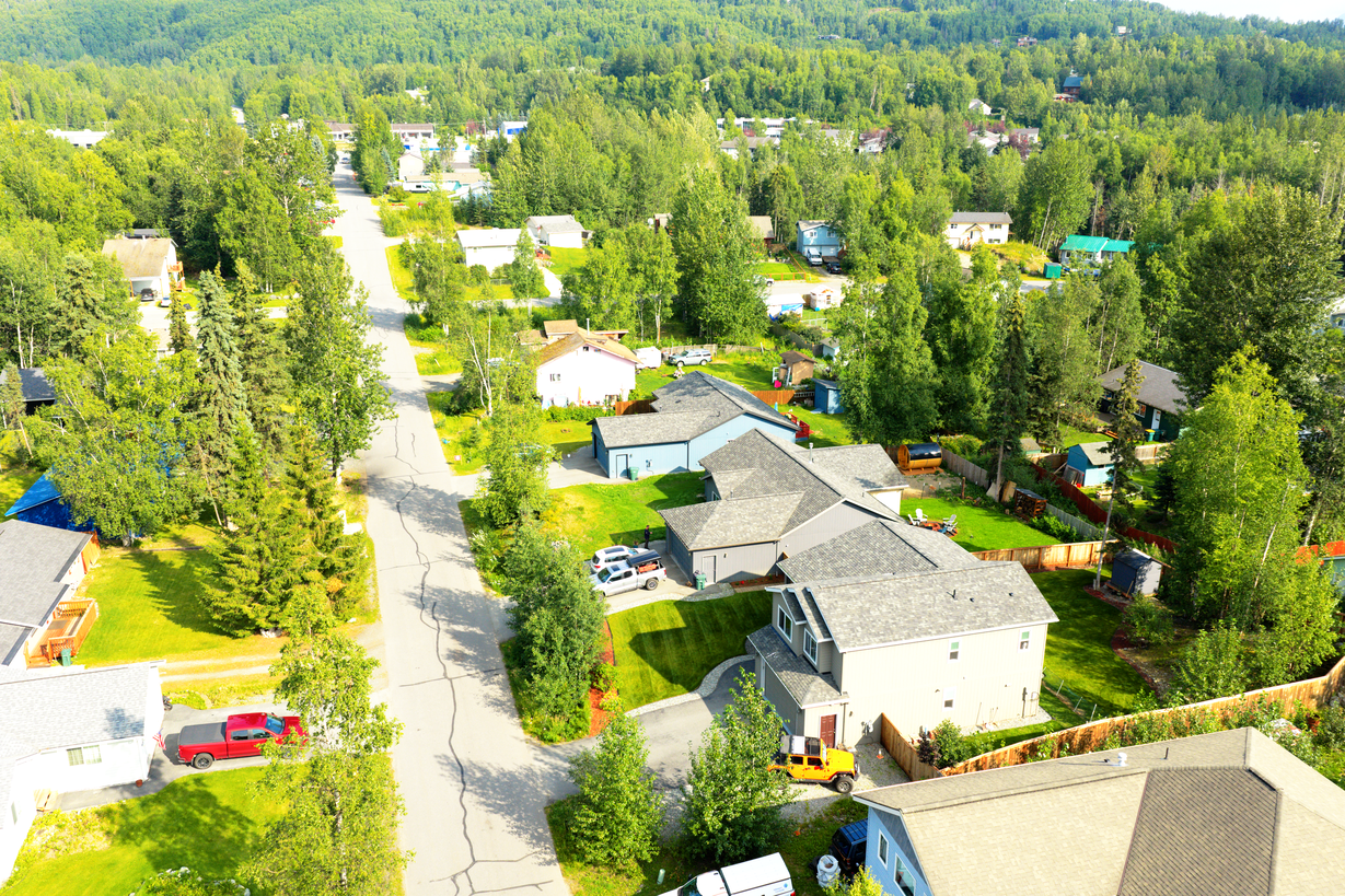 High aerial drone overview of an Alaska property and surrounding neighborhood